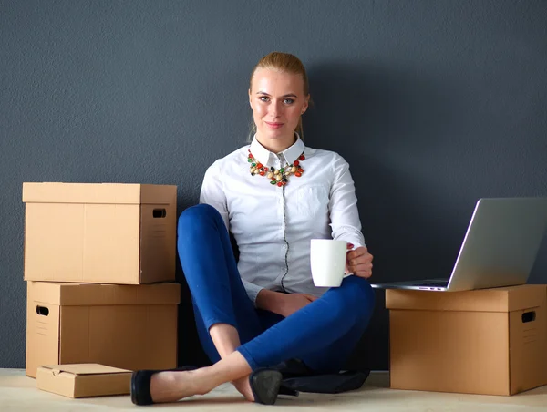 Frau sitzt auf dem Boden neben einer Schachtel mit Laptop — Stockfoto