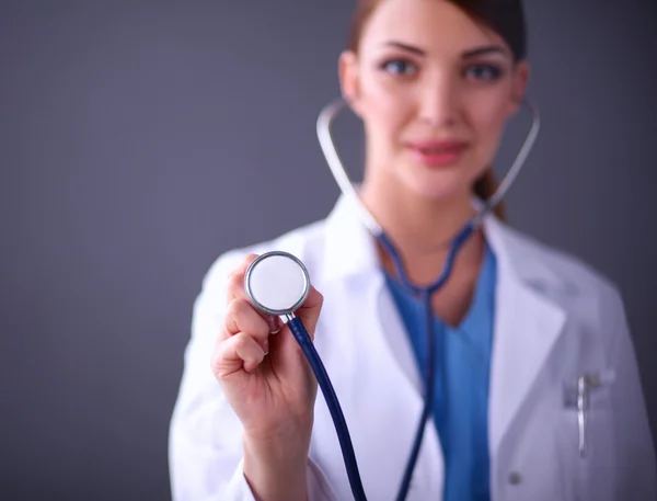 Female doctor with a stethoscope listening, isolated on grey background — Stock Photo, Image