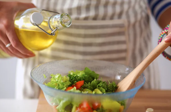 Mujer joven mezclando ensalada fresca, de pie cerca del escritorio —  Fotos de Stock