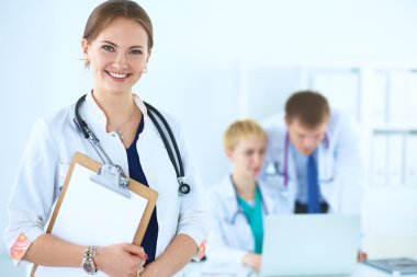 Tıbbî grubun önünde dosyası olan çekici bir kadın doktor.