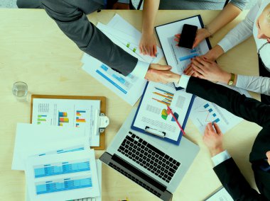 İş adamları el sıkışır, masada otururlar.