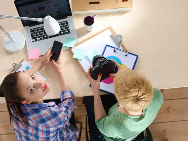 Vrouwelijke fotograaf zittend op het bureau met laptop — Stockfoto