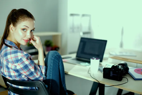 Kvinnlig fotograf sitter på skrivbordet med bärbar dator — Stockfoto
