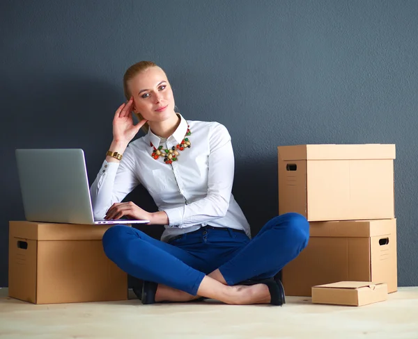 Frau sitzt auf dem Boden neben einer Schachtel mit Laptop — Stockfoto