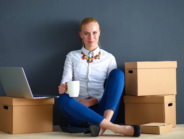 一个女人坐在一个装有笔记本电脑的盒子旁边的地板上 — 图库照片