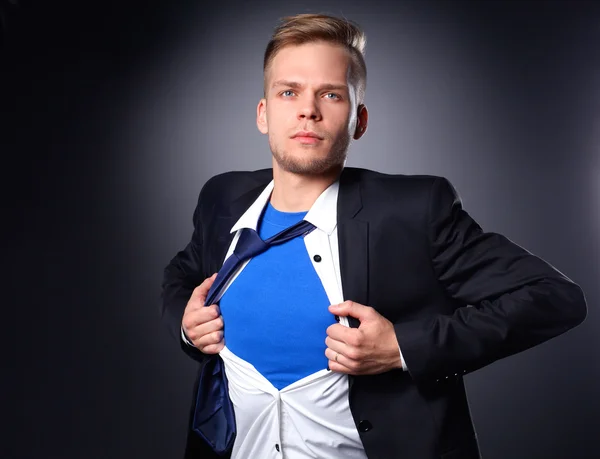 Ung affärsman agerar som en super hjälte och riva sin skjorta, isolerad på grå bakgrund — Stockfoto