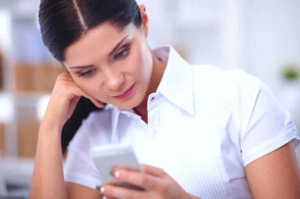 Businesswoman sending message with smartphone sitting in the office — Stock Photo, Image