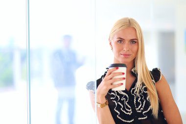Ofiste kahve içen genç bir kadın.