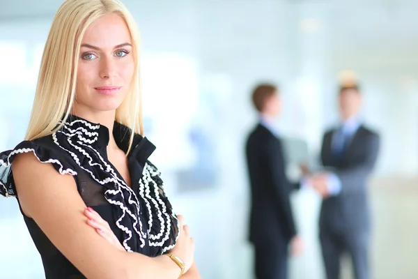 Business woman standing in foreground with a tablet in her hands — Stock Photo, Image