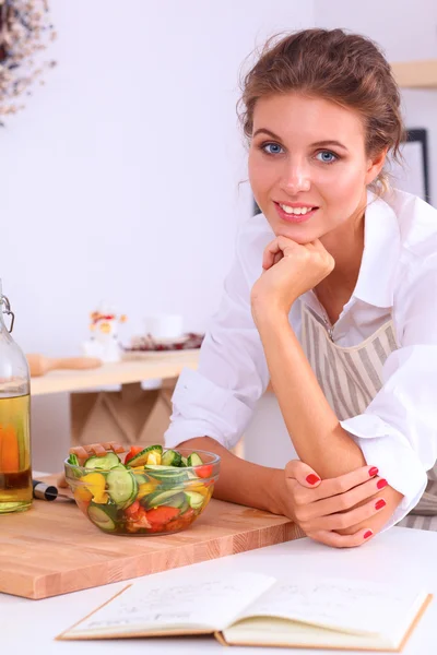 Sorrindo jovem mulher preparando salada na cozinha — Fotografia de Stock