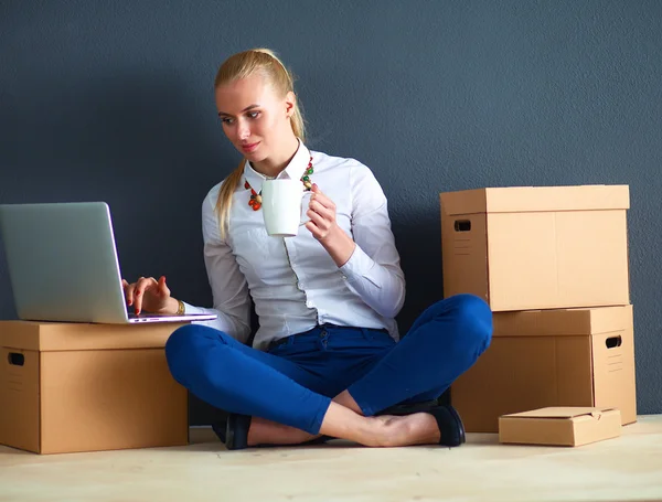 Frau sitzt auf dem Boden neben einer Schachtel mit Laptop — Stockfoto