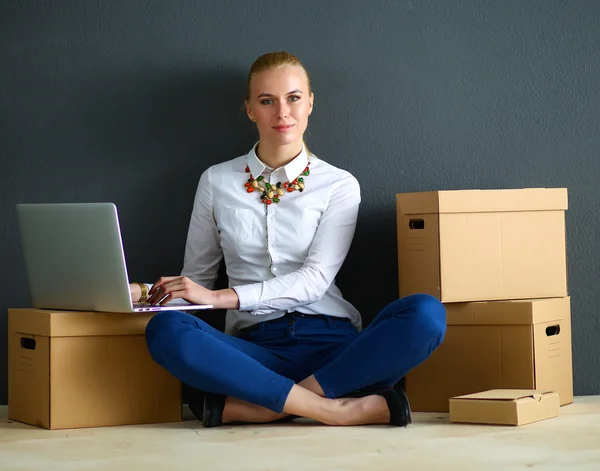 Mujer sentada en el suelo cerca de una caja con portátil —  Fotos de Stock