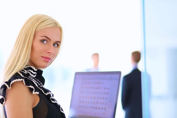 Joven mujer de negocios sosteniendo un portátil, de pie en la oficina — Foto de Stock