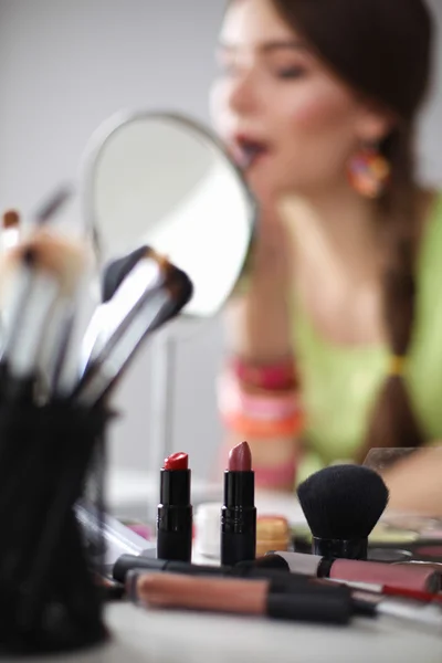 Jonge mooie vrouw maken make-up in de buurt van spiegel, zitten aan de balie — Stockfoto