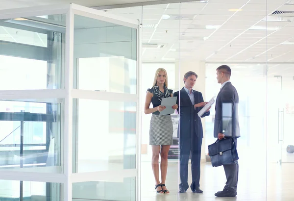 Donna d'affari in piedi con il suo personale in background in ufficio moderno — Foto Stock