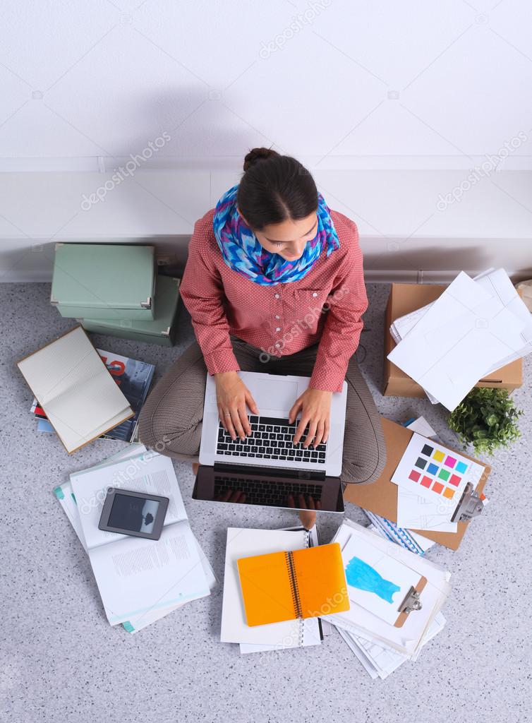 Young attractive female fashion designer working at office desk, drawing while talking on mobile