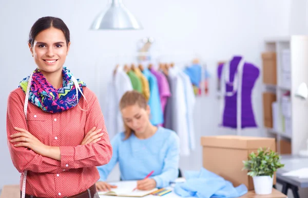 Ofis masasında çalışan genç, çekici bayan moda tasarımcısı, cep telefonuyla konuşurken çizim yapıyor. — Stok fotoğraf