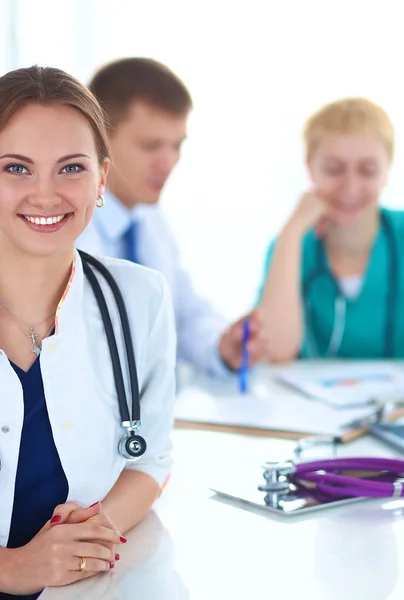 Beautiful young smiling female doctor sitting at the desk — Stock Photo, Image