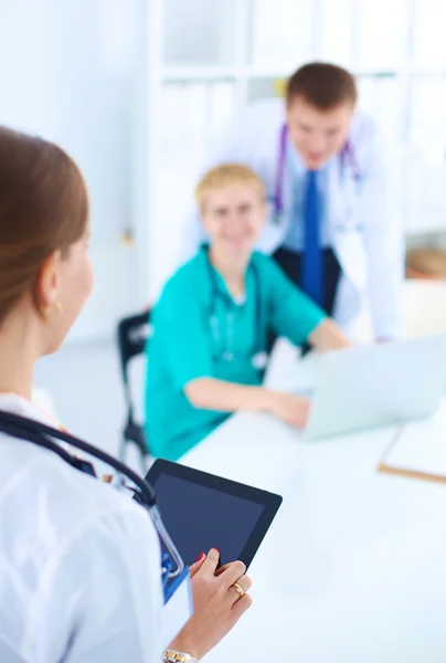 Bella giovane sorridente medico femminile seduto alla scrivania — Foto Stock