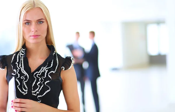 Business woman standing in foreground with a tablet in her hands — Stock Photo, Image