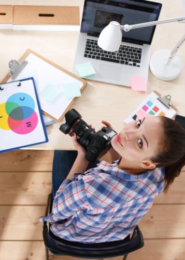 Masada dizüstü bilgisayarla oturan kadın fotoğrafçı.