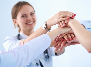Doktorlar ve hemşireler tıbbi bir ekipte el ele tutuşuyorlar. 