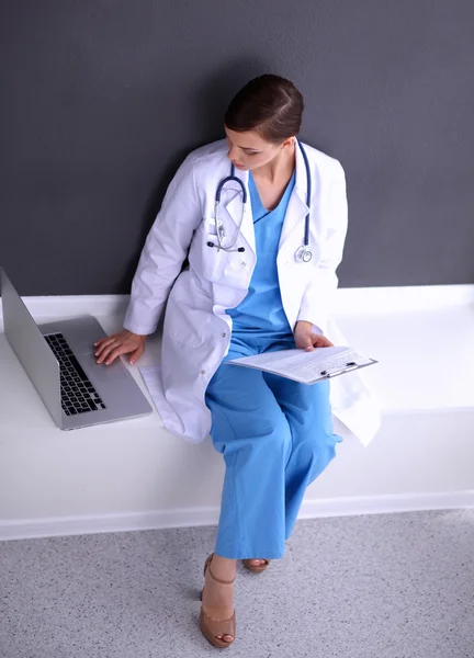Nurse holding folder en het maken van aantekeningen - zitten op grijze achtergrond — Stockfoto