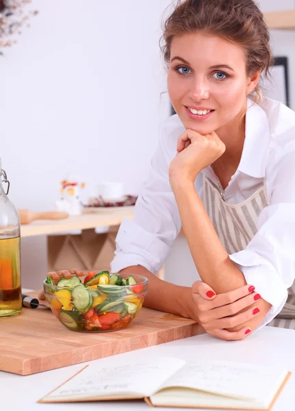 Mujer joven sonriente preparando ensalada en la cocina — Foto de Stock