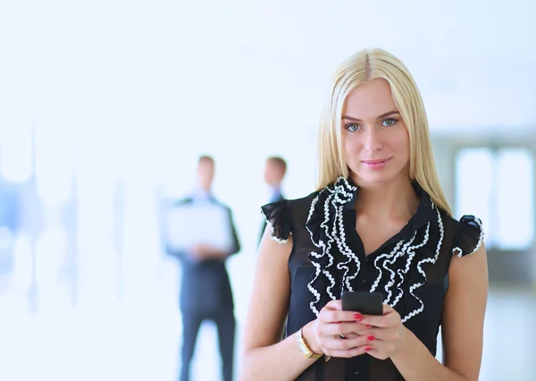 Vacker affärskvinna med mobiltelefon, stående på kontoret — Stockfoto