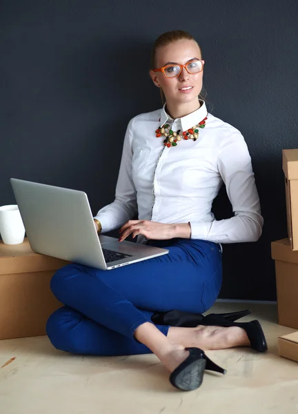 Frau sitzt auf dem Boden neben einer Schachtel mit Laptop — Stockfoto