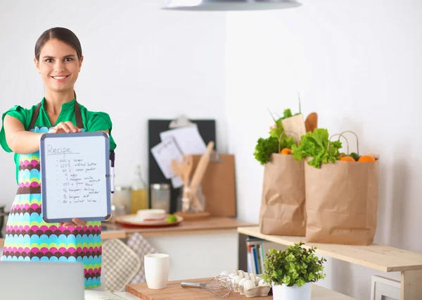 Женщина на кухне дома, стоящая возле стола с папкой — стоковое фото