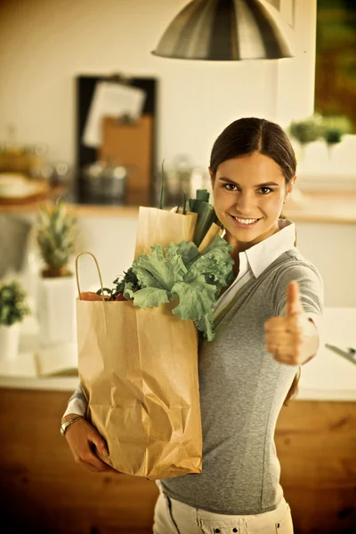 Mujer joven sosteniendo bolsa de la compra de comestibles con verduras y mostrando ok —  Fotos de Stock