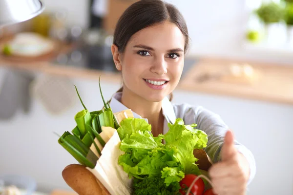 Молодая женщина держит продуктовый пакет с овощами и показывает в порядке — стоковое фото