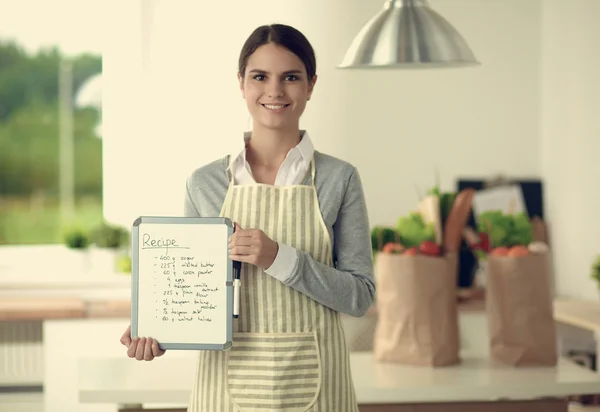 Woman in the kitchen at home, standing near desk with folder — Stock Photo, Image