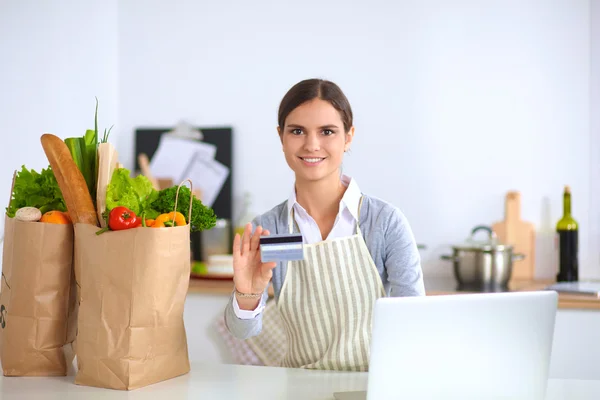 在厨房用电脑和信用卡让女人在网上购物 — 图库照片