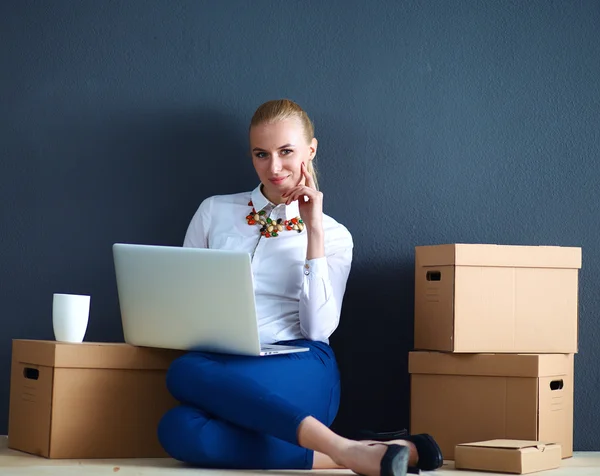 Woman sitting on the floor near a boxes  with laptop — Stock Photo, Image