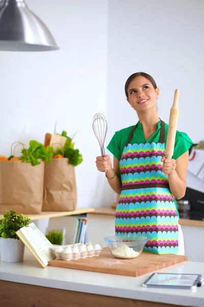 Sorridente giovane donna in cucina, isolata sullo sfondo — Foto Stock