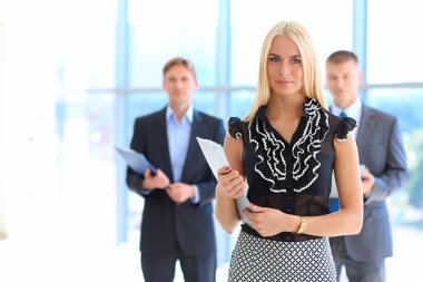 İçinde belgili tanımlık geçmiş meslektaşları ile bir ofiste duran bir güzel ofis çalışanı portresi