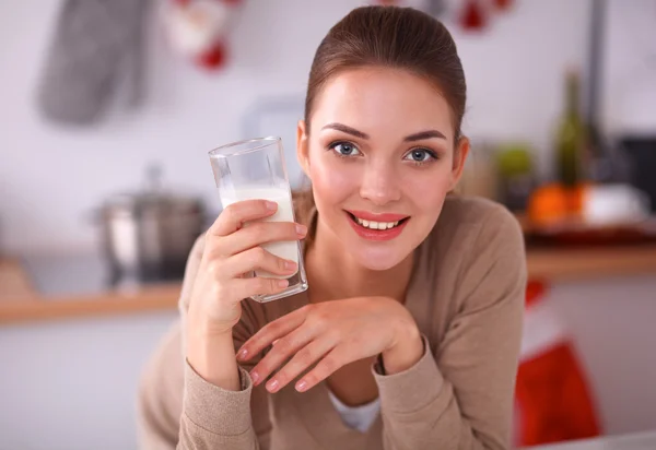 En ung kvinna med ett glas mjölk i hennes kök — Stockfoto