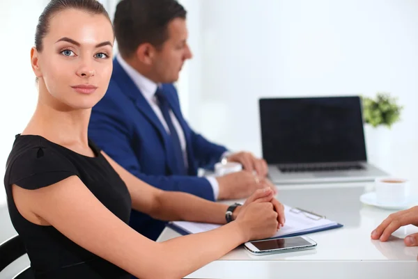 Porträtt av en vacker affärskvinna som sitter på ett kontor med kollegor i bakgrunden — Stockfoto