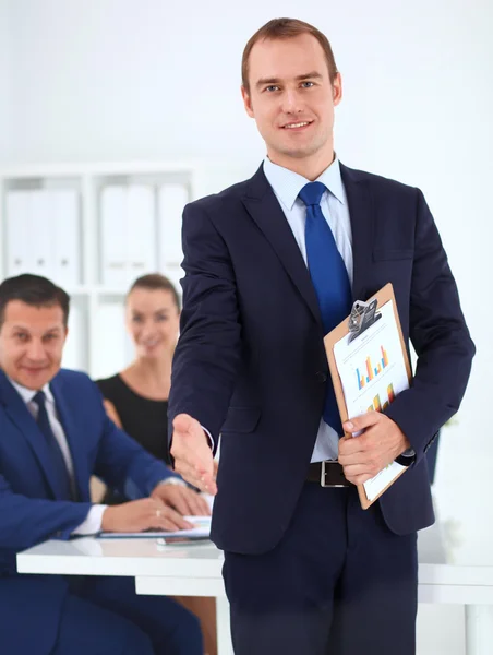 Porträt eines gutaussehenden Geschäftsmannes beim Händedruck mit Kollegen im Hintergrund — Stockfoto