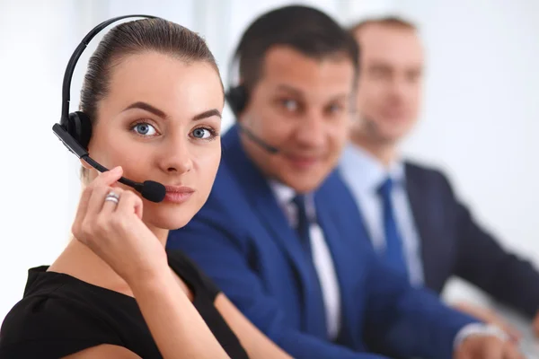 Retrato de mulher de negócios bonita em fones de ouvido sorrindo com colegas de fundo — Fotografia de Stock