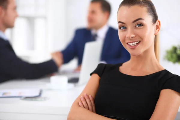 Portrait of a beautiful businesswoman standing in an office with colleagues in the background — Stock Photo, Image