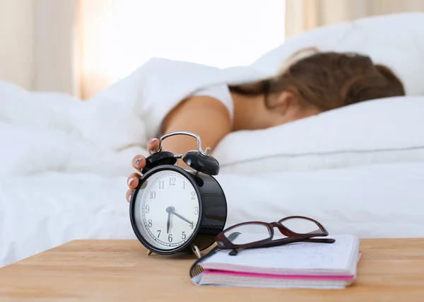 En ung kvinna stänger av väckarklockan på morgonen. — Stockfoto