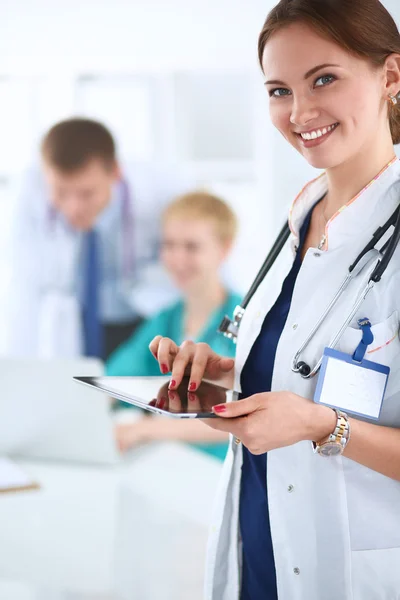 Happy medical doctor with her colleagues in the background — Stock Photo, Image