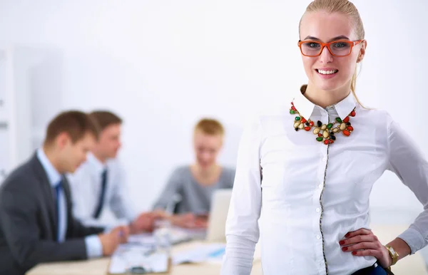 Porträt einer schönen Büroangestellten, die in einem Büro steht, mit Kollegen im Hintergrund — Stockfoto