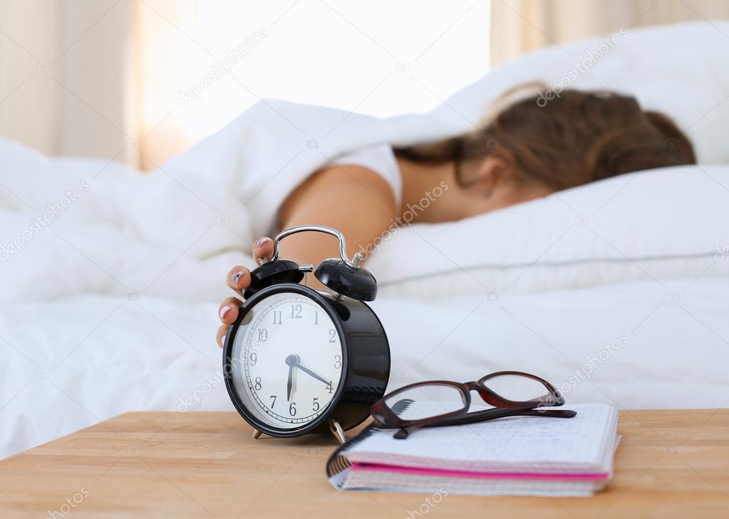 A young woman putting her alarm clock off in the morning