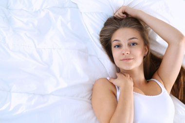 Genç ve güzel bir kadın yatakta yatıyor.