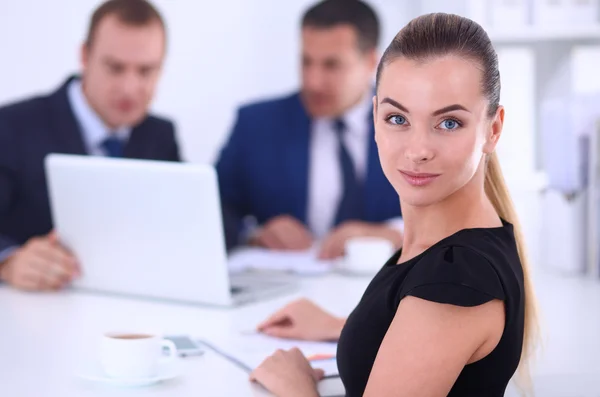 Portret van een mooie zakenvrouw zitten in een kantoor met collega's op de achtergrond — Stockfoto