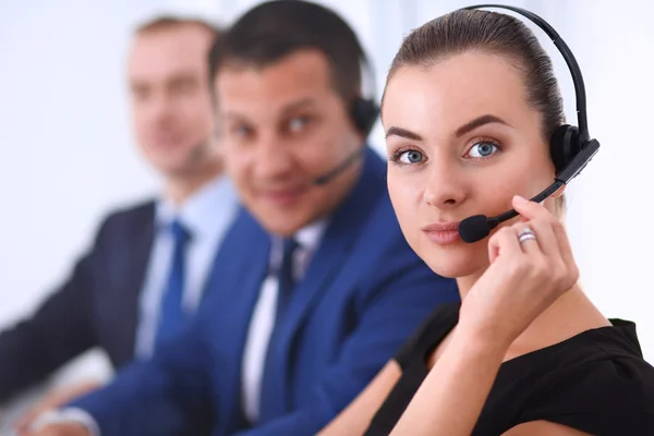 Retrato de mujer de negocios hermosa en auriculares sonriendo con colegas de fondo — Foto de Stock